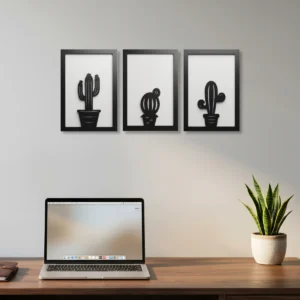 Conjunto de três quadros decorativos em MDF com duas camadas, com desenhos vazados de diferentes cactos na cor preto e branco, instalados na parede de um escritório.
