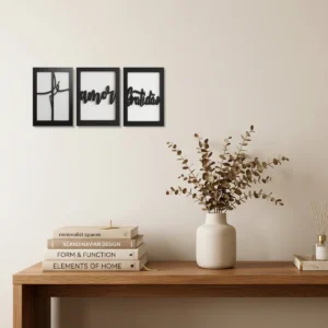 Conjunto de três quadros decorativos em MDF com duas camadas, com as palavras vazadas Fé, Amor e Gratidão na cor preto e branco, instalados na parede de um escritório.