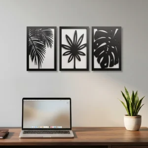 Conjunto de três quadros decorativos em MDF com duas camadas, com desenhos vazados de plantas e flores na cor preto e branco, instalados na parede de um escritório moderno.
